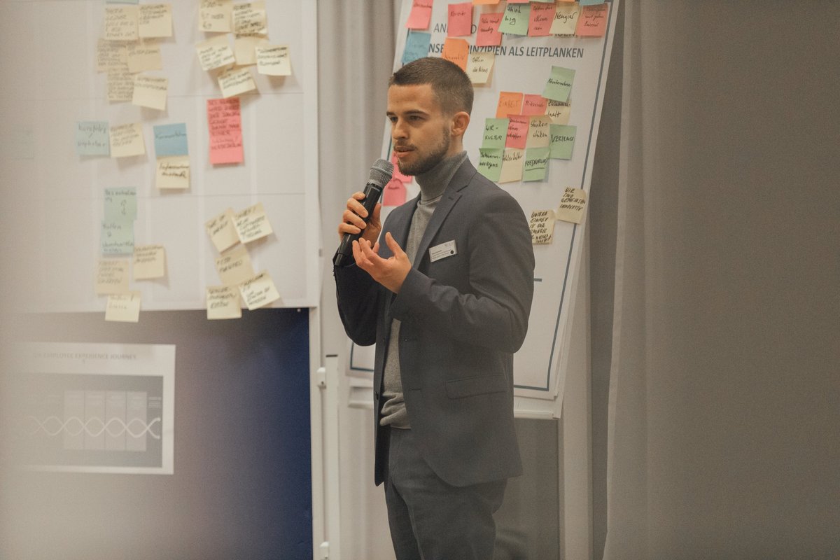 Timo Schroeder moderiert einen Workshop vor Pinnwänden mit Moderationskarten